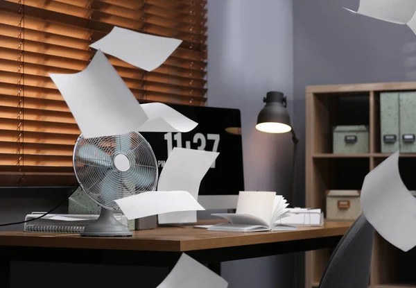 Modern electric fan and flying paper in office