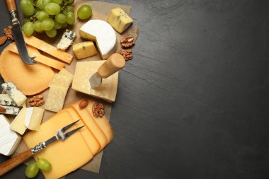 Düz kompozisyon, farklı peynir çeşitleri ve bıçaklarla siyah masanın üzerinde yatıyordu. Metin için boşluk