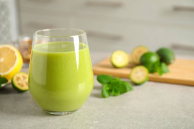 Açık gri masada cam içinde taze feijoa smoothie, yakın plan. Metin için boşluk