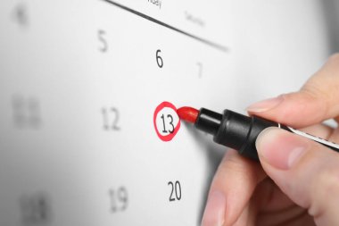 13. Cuma 'yı takvimde işaretleyen kadın, yakın plan. Kötü şans batıl inanç.