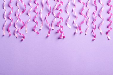 Açık mor arka planda pembe serebentin şeritler, düz bir zemin. Metin için boşluk