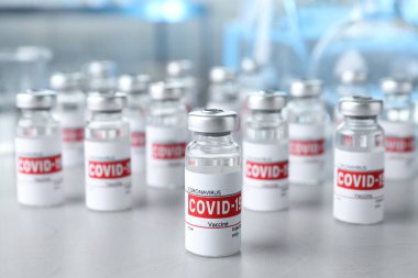 Işık masasının üzerinde COVID-19 aşısı olan cam şişeler.