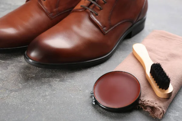 Shoe care products and footwear on grey stone table, closeup