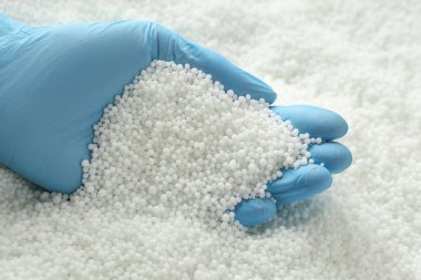 Eldivenli biri yığından amonyum nitrat topakları alıyor, yakın plan. Mineral gübresi