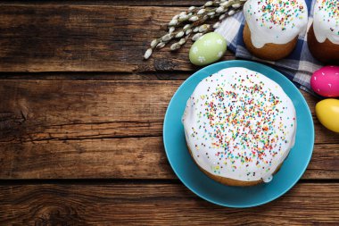 Traditional Easter cake, pussy willows and colorful eggs on wooden table, flat lay. Space for text