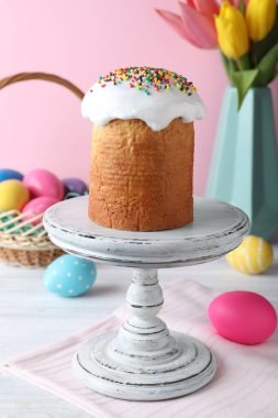 Paskalya pastası, beyaz ahşap masada renkli yumurtalar ve laleler.