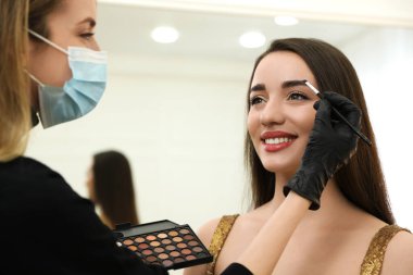 Profesyonel makyöz müşteriyle kuaförde çalışıyor. Coronavirus karantinası sırasında güzellik hizmetleri