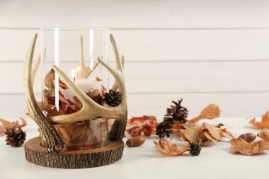 Beyaz ahşap masa üzerinde yanan mum ve sonbahar dekoru olan şık bir tutucu. Metin için boşluk