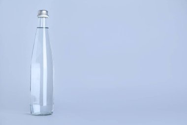 Açık gri zemin üzerinde su olan cam şişe, metin için boşluk