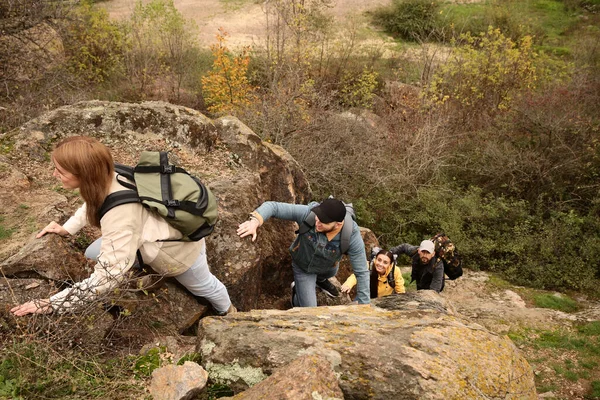 Group of hikers with backpacks climbing up mountains