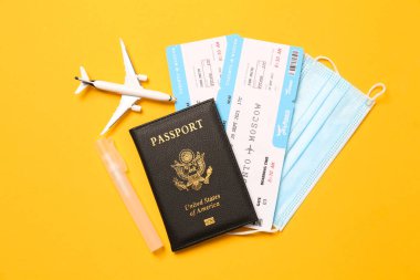 Sarı arka planda pasaport ve koruyucu maskeli düz kompozisyon. Karantina sırasında seyahat