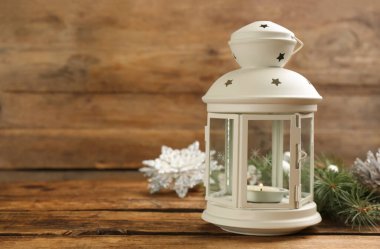 Yanan mumlu Noel feneri ve ahşap masada şenlikli bir dekor. Metin için boşluk