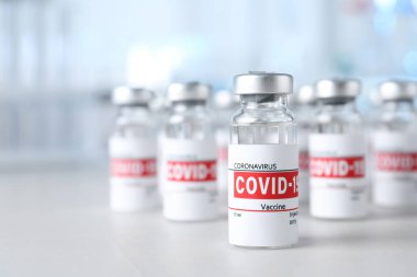 Işık masasının üzerinde COVID-19 aşısı olan cam şişeler. Metin için boşluk