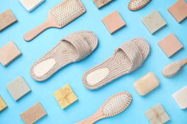 Terlikler, saç fırçaları ve açık mavi arka planda sabunlar, düz yatış