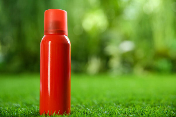 Бутылка спрея от насекомых на зеленой траве. Пространство для текста