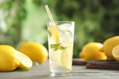 Soğuk taze limonata ve gri ahşap masada meyveler.