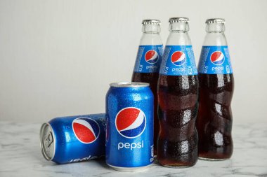 MYKOLAIV, UKRAINE - 9 Şubat 2021: Beyaz mermer masa üzerinde birçok şişe ve kutu Pepsi