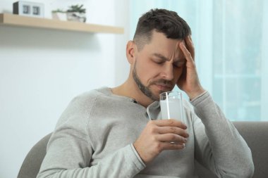 Akşamdan kalma olmak için ilaç alan bir adam.