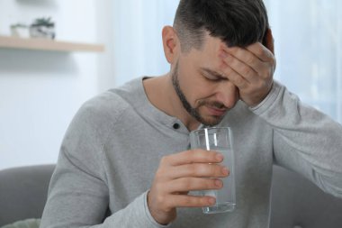 Akşamdan kalma olmak için ilaç alan bir adam.