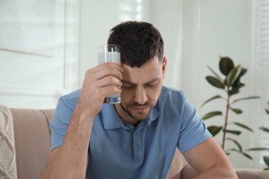 Akşamdan kalma olmak için ilaç alan bir adam.