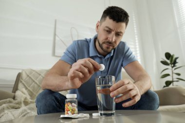 Akşamdan kalma olmak için ilaç alan bir adam.