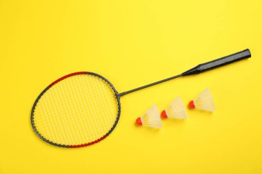 Sarı arka planda raket ve mekiklerin horozu düz yatıyordu. Badminton ekipmanı