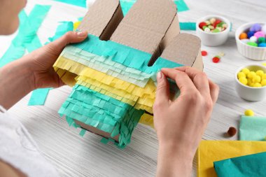 Beyaz ahşap masada karton kaktüs dekore eden kadın, yakın plan. Pinata DIY