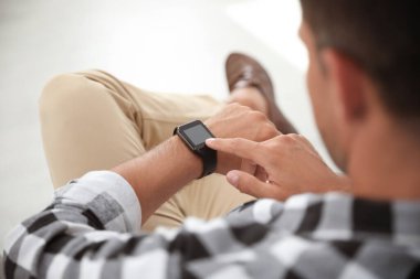 Bulanık arkaplanda akıllı saati olan adam, yakın plan