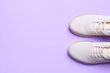 Açık mor arka planda şık spor ayakkabılar, üst manzara. Metin için boşluk