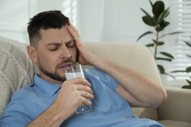 Akşamdan kalma olmak için ilaç alan bir adam.