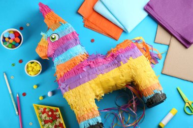 Mavi arka planda karton eşekle ve malzemelerle düz kompozisyon. Pinata diy