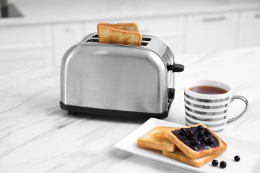 Mutfaktaki beyaz mermer masada modern tost makinesi ve lezzetli kahvaltı