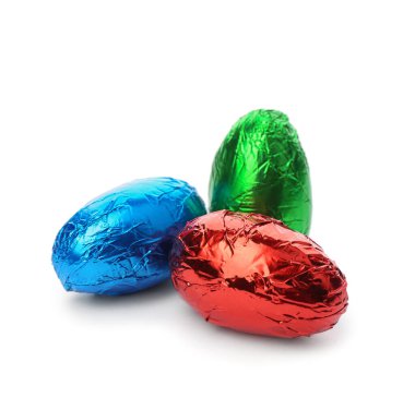 Beyaz arka planda parlak folyoya sarılı çikolatalı yumurtalar.