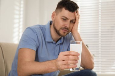 Akşamdan kalmalık için ilaç alan adam, elinde cam olan ele odaklan.