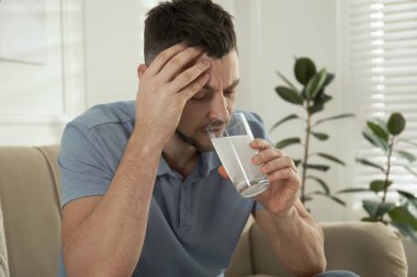 Akşamdan kalma olmak için ilaç alan bir adam.