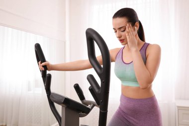 Evde modern eliptik makine eğitiminden sonra yorgun bir kadın.