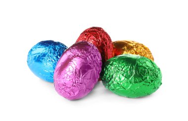 Beyaz arka planda renkli folyoya sarılı çikolatalı yumurtalar.