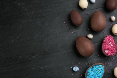 Tatlı çikolatalı yumurtalar ve siyah masaya serpiştirilmiş şekerlemeler. Metin için boşluk