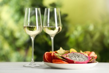 Lezzetli egzotik meyveler ve şarap beyaz masada.