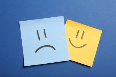 Mavi arka planda üzgün ve mutlu yüzleri olan çıkartmalar, düz yatıyordu.