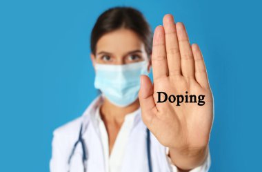 Koruyucu maskeli doktor mavi arka plana karşı dur hareketi gösteriyor. Eline odaklan. Doping kontrolü
