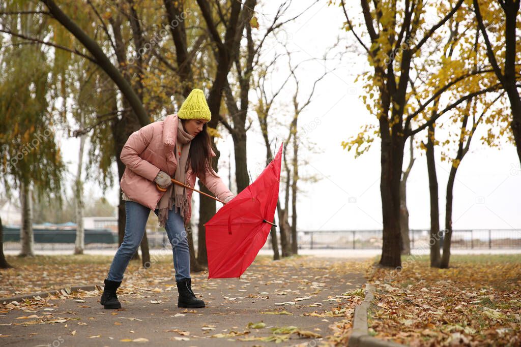 Woman with red umbrella caught in gust of wind outdoors