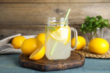 Serin taze limonata ve açık mavi ahşap masada meyveler.