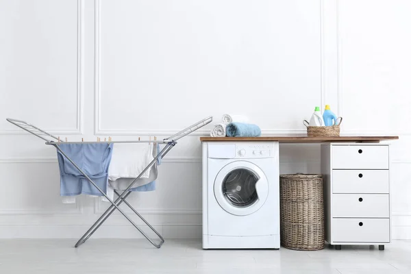 Clean laundry hanging on drying rack indoors