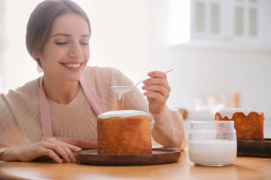 Genç bir kadın geleneksel paskalya pastasını mutfakta jöleli dekore ediyor. Metin için boşluk