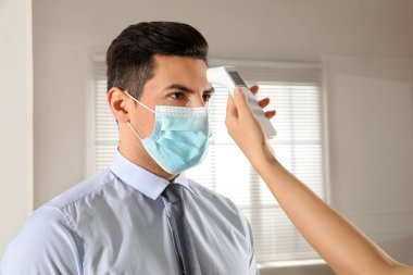 Doktor ofisteki adamın ateşini ölçüyor. Covid-19 'un yayılmasını engelle