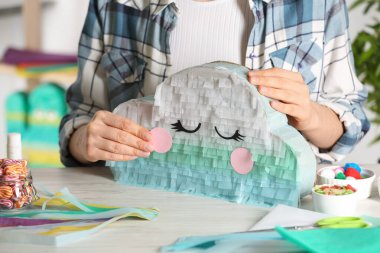 Beyaz ahşap masada karton bulutlar süsleyen kadın, yakın plan. Pinata diy