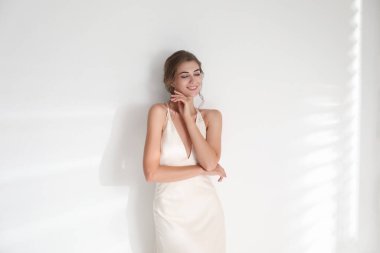 Genç gelin, açık arkaplanda güzel bir gelinlik giyiyor.