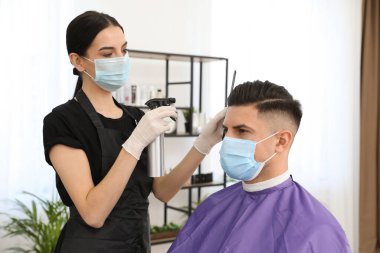 Müşteriyle kuaförde çalışan profesyonel stilist. Coronavirus karantinası sırasında kuaför servisi