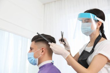 Müşteriyle kuaförde çalışan profesyonel stilist. Coronavirus karantinası sırasında kuaför servisi